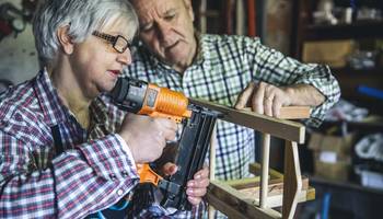Repair Café Älteres Ehepaar baut gemeinsam etwas aus Holz