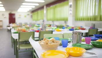 Eine Mensa oder Cafeteria mit gedeckten Tischen.